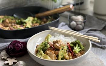 Rezept Asia-Hähnchen-Pfanne auf Teller angerichtet - im Hintergrund Keramikpfanne