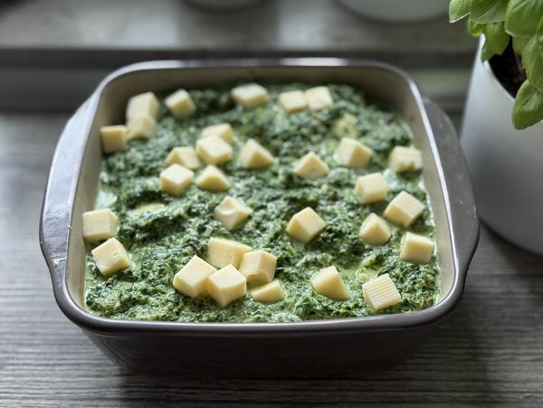 Knutschis in Spinatsosse - Gericht ungebacken Gericht vor dem Backen mit Käse bestreut für Rezept Knutschis in Spinatsosse