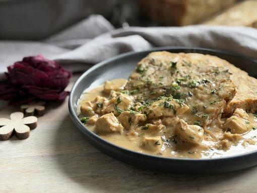 Semmelknödel Rezept - angerichtet Semmelknödel mit Soße auf Teller angerichtet im Hintergrund kleiner Ofenmeister von Pampered Chef®