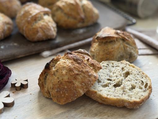 Aufgeschnittenes Brötchen auf Teller - im Hintergrund Brötchen auf Zauberstein 
