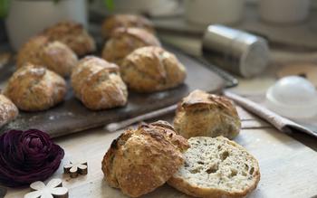 Aufgeschnittenes Brötchen auf Teller - im Hintergrund Brötchen auf Zauberstein 