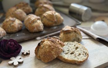 Aufgeschnittenes Brötchen auf Teller - im Hintergrund Brötchen auf Zauberstein 