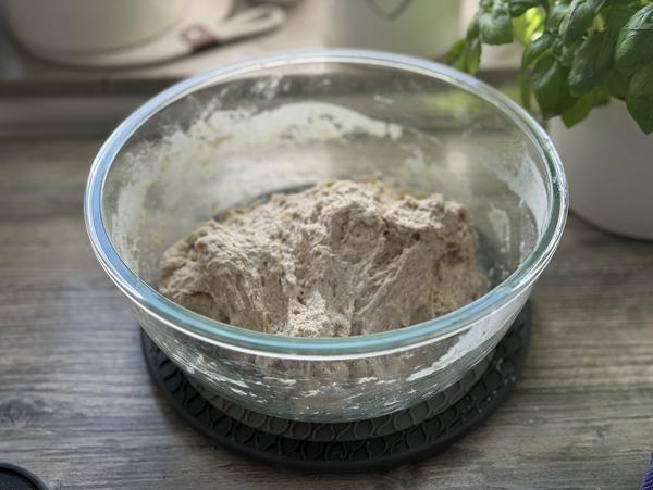 Haferbrot Rezept – Teig mit Haferflocken verrühren Frisch verrührter Haferbrot-Teig mit Haferflocken in einer Glasschüssel auf einem Holztisch