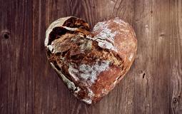 Gebackenes Brot in Herzform auf Holzuntergrund