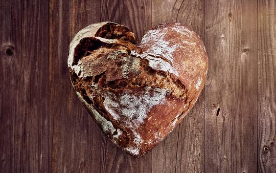 Allgemeines über Brot Gebackenes Brot in Herzform auf Holzuntergrund
